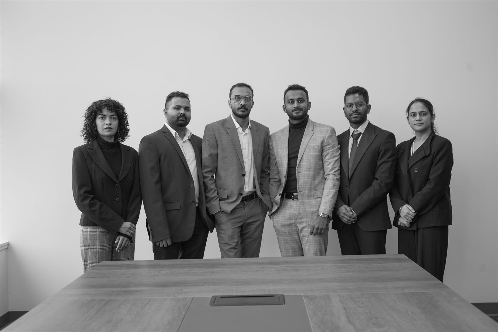 The Nexsure team, six people in business dress, standing behind a boardroom table